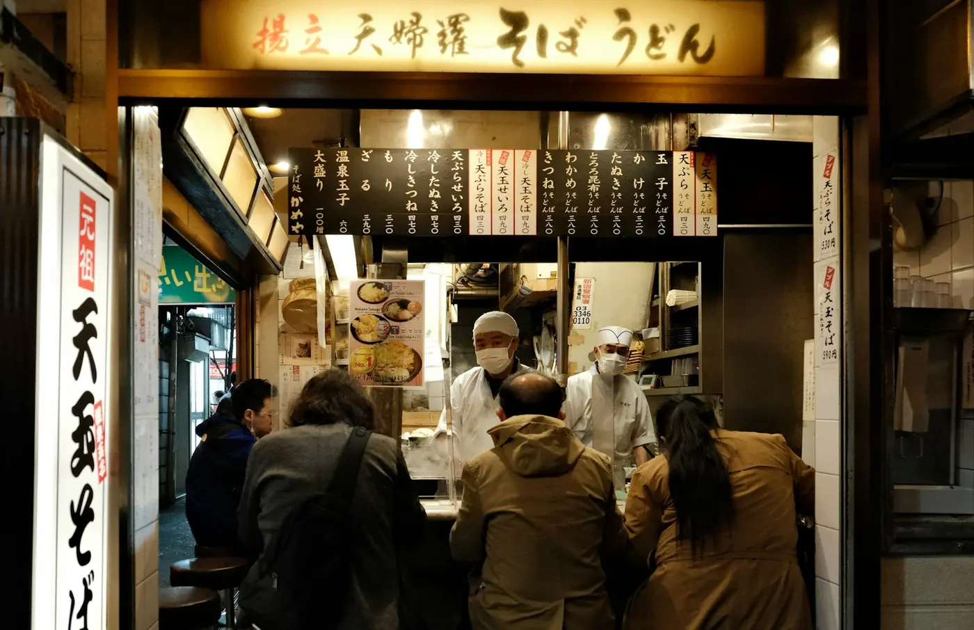 People at the counter of a small soba shop